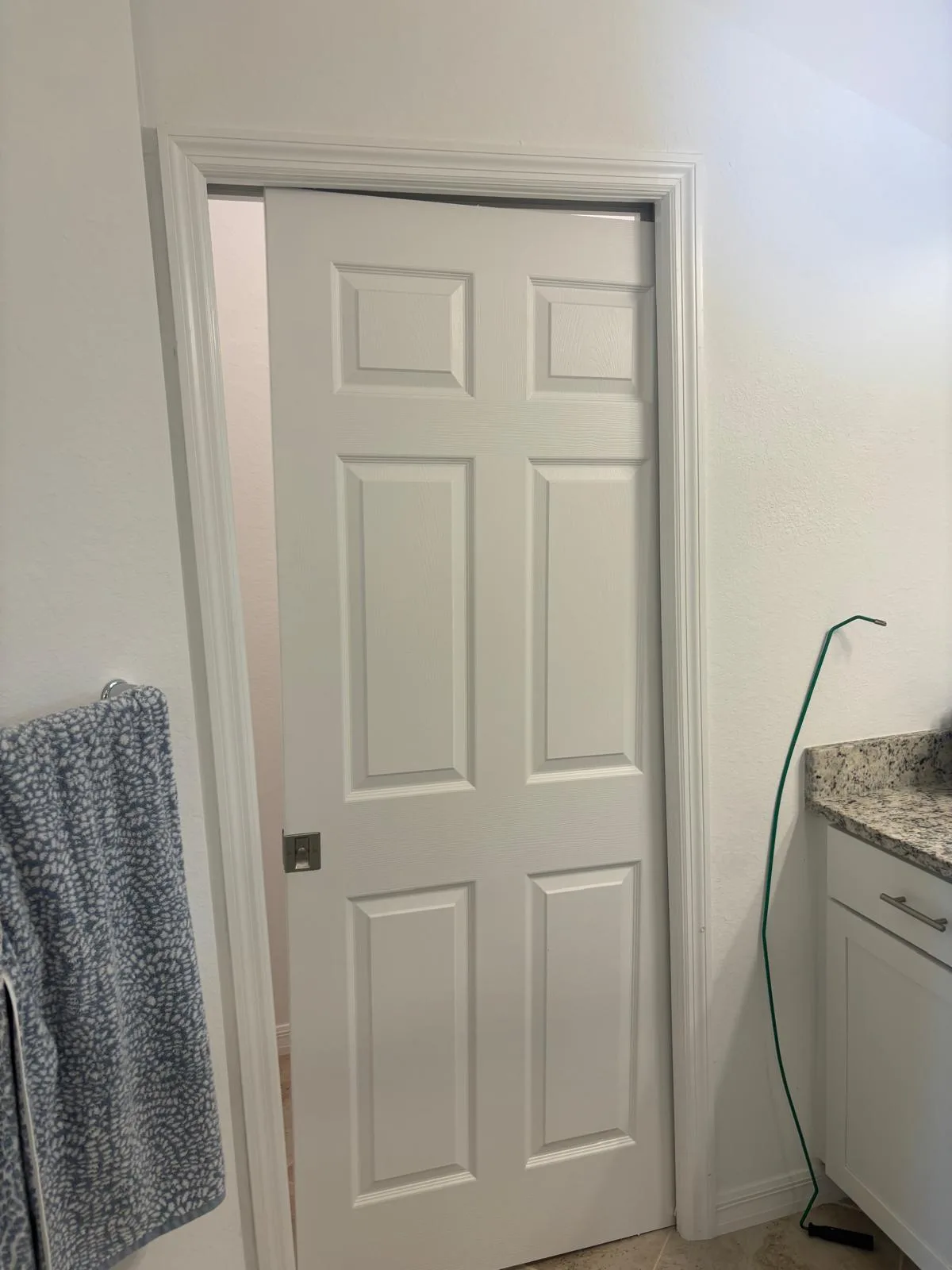 Pocket door lifted off its bottom track during repair at a River Park home showing worn guide hardware and debris buildup.